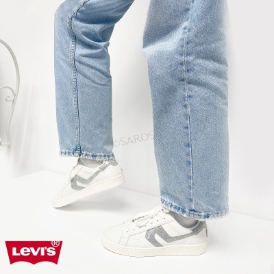 Tênis brancos com padrão cinzento brilhante usados com jeans azuis
