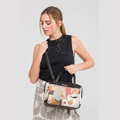 Mulher com mala de mão Anekke com padrão abstrato colorido e vestuário preto e creme