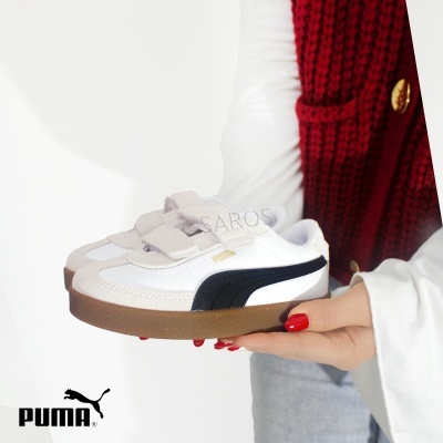 Ténis Puma branco com solado castanho e detalhes pretos, tiras de velcro, segurado por pessoa com camisa branca e colete vermelho.