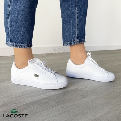 Sapatilhas brancas Lacoste com logótipo verde usadas com jeans