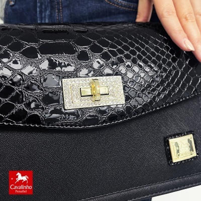 Mala preta com textura de pele de crocodilo e fecho metálico com cristais
