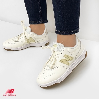 Ténis New Balance branco com detalhes em bege usados com calças jeans