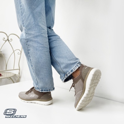 Ténis Skechers bege e castanho com sola branca e calças de ganga azuis claras