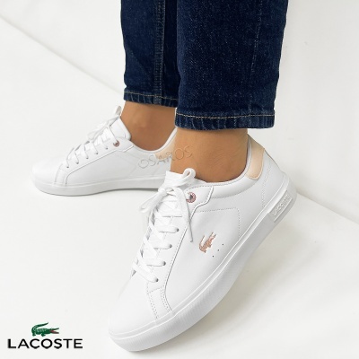 Sapatilhas brancas Lacoste com logo rosa metálico e detalhe bege usadas com jeans azuis