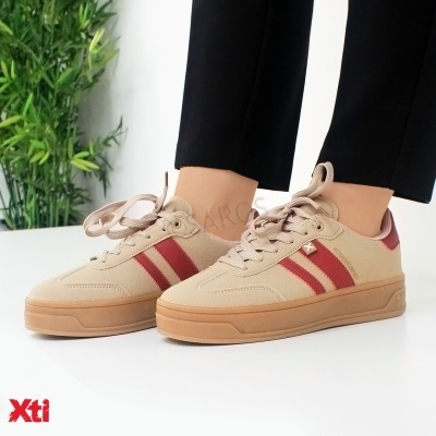 Ténis bege com riscas vermelhas e sola cor caramelo, pessoas a usar, fundo branco com planta verde