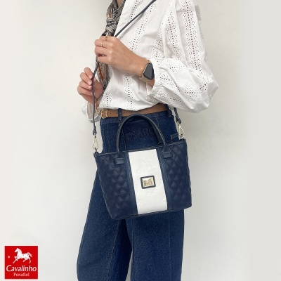 Mala Cavalinho azul e branca usada por mulher com camisa branca e jeans