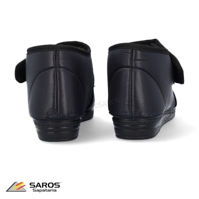 Sapatos pretos em material sintético com velcro, vistos de trás em fundo branco