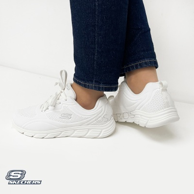 Sapatilhas brancas Skechers com atacadores e sola branca usadas com calças azul-escuras