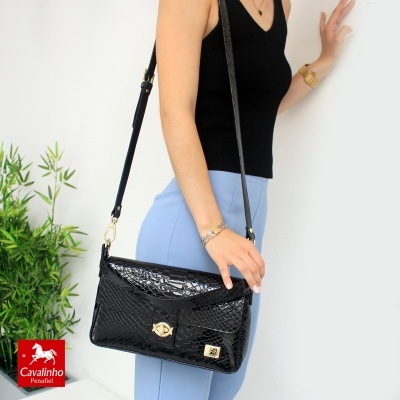 Bolsa preta croco com alça dourada e mulher com roupa preta e azul