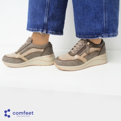 Sapatilhas castanhas com solado branco e zíper lateral, com calças de ganga azuis.