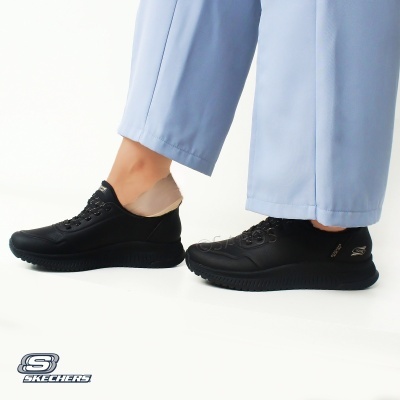 Ténis Skechers pretos com sola e atacadores pretos, usados com calças azuis claras