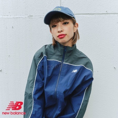 Casaco desportivo New Balance azul e cinza com logótipos visíveis e uma pessoa a usá-lo