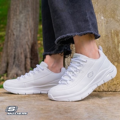 Ténis brancos Skechers com sola grossa e design moderno colocados no chão exterior junto a uma árvore