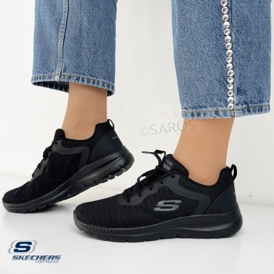 Ténis pretos Skechers com sola preta junto a jeans azuis com botões