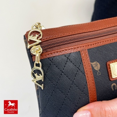 Mala preta com padrão e detalhes castanhos e pendura dourado com texto Cavalinho