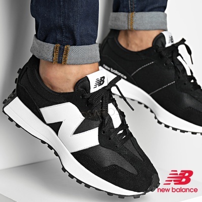 Ténis desportivos New Balance pretos e brancos usados por pessoa com jeans