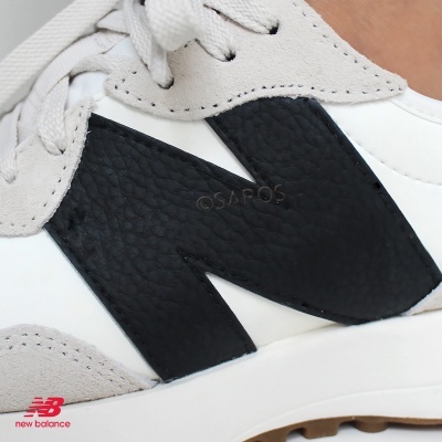 Sapatilha New Balance branca com detalhes cinza e logótipo preto texturizado na lateral.