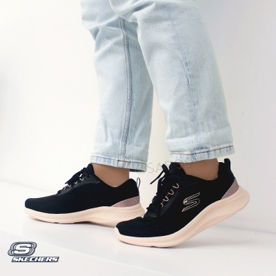 Ténis Skechers pretos com sola bege e detalhes prateados usados com jeans claros