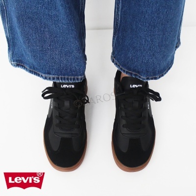Ténis pretos Levi's com sola castanha usados com jeans azuis