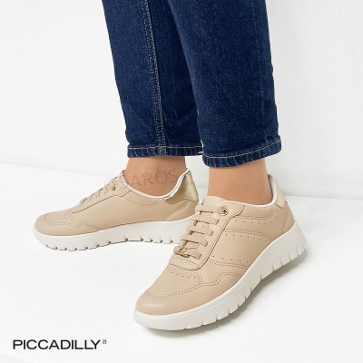 Ténis bege claro com sola branca e detalhe dourado usados com jeans azul escuro