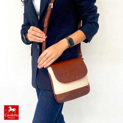 Mala de ombro castanha e creme Cavalinho usa por mulher com blazer azul