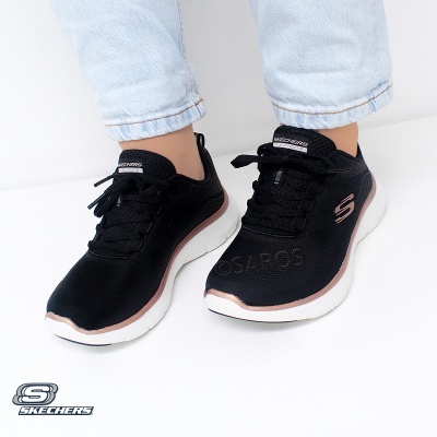 Ténis Skechers pretos com detalhes rosa dourado e sola branca usados com calças de ganga
