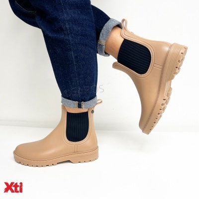 Botins bege com elástico preto e sola robusta da marca Xti, usados com jeans azul