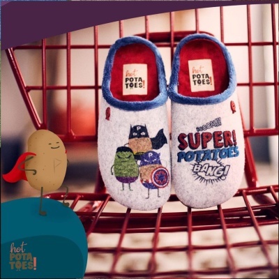 Pantufas infantis cinza com estampas coloridas de batatas superheroínas sentadas numa cadeira vermelha de metal