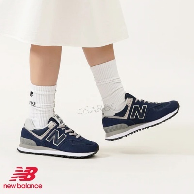 Ténis New Balance azuis com detalhes cinza e brancos, usados com meias brancas caneladas.