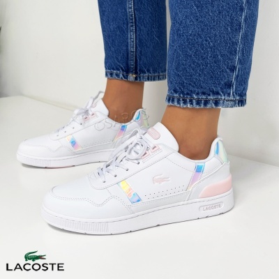 Ténis brancos Lacoste com detalhes iridescentes e rosa usados por pessoa com jeans
