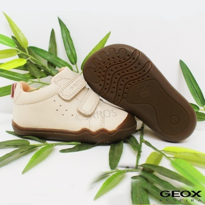 Sapatos infantis Geox bege com sola castanha em fundo branco e folhas verdes