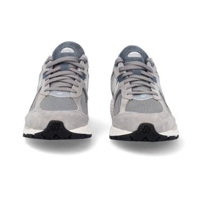 Ténis New Balance cinzentos vistos de frente, com sola preta e branca.