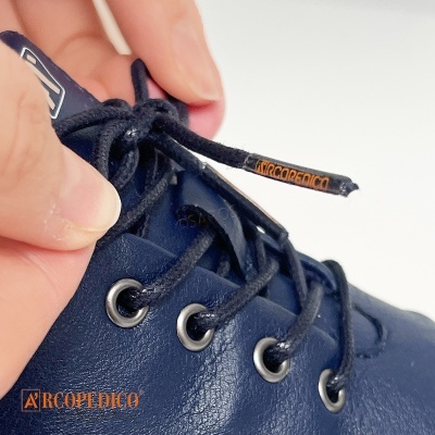 Sapato azul escuro com atacadores pretos e detalhes em laranja, fundo branco