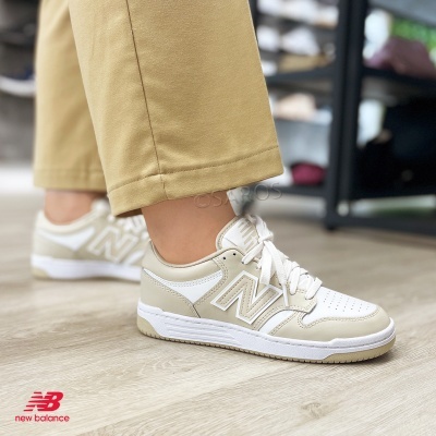 Ténis New Balance bege claro e branco em chão de madeira