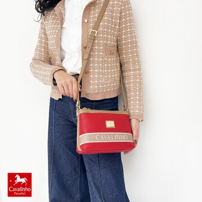 Bolsa de ombro vermelha com faixa bege CAVALINHO e mulher com casaco castanho claro e camisa branca