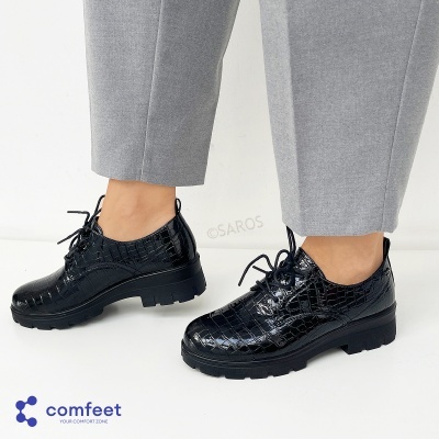 Sapatos pretos de verniz com padrão crocodilo usados com calças cinzentas