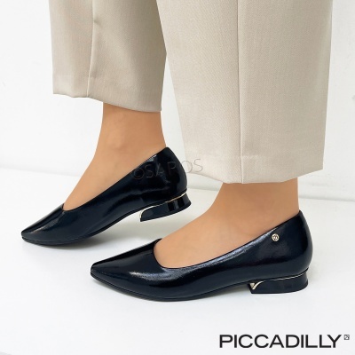 Sapatos planos pretos em verniz com salto baixo decorado, usados com calças bege