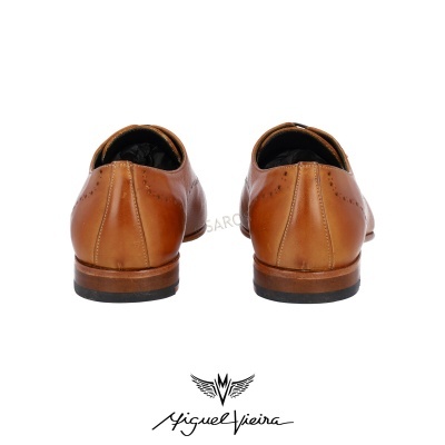 Sapatos de couro castanhos vistos de trás com assinatura e símbolo abaixo