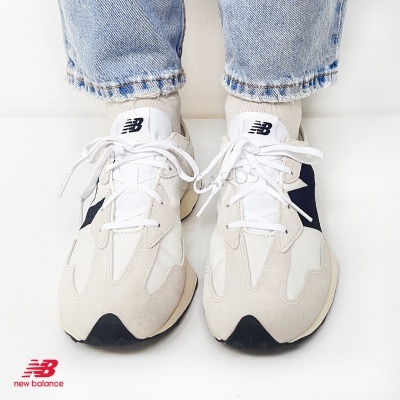 Ténis New Balance bege com detalhes em branco e preto, usados com meias brancas e ganga azul claro