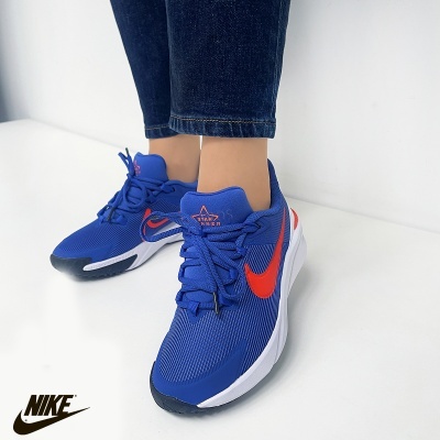 Ténis Nike azuis com swoosh vermelho e sola branca usados com calças jeans