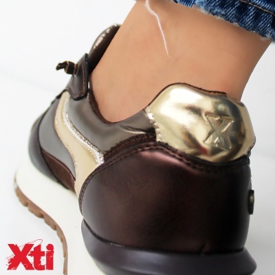 Ténis castanho e dourado com sola branca assinados pela marca Xti