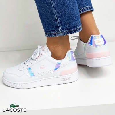 Ténis Lacoste brancos com detalhes iridescentes usados com calças de ganga azuis