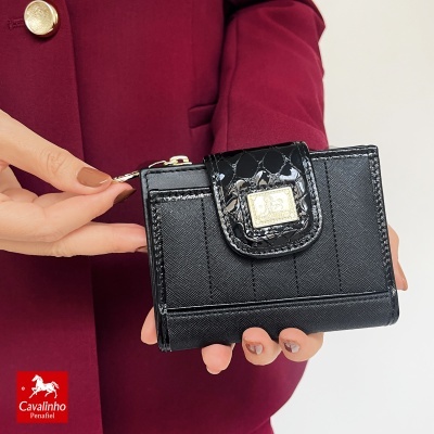 Carteira preta elegante com fecho e placa dourada, segurada por pessoa com casaco bordô