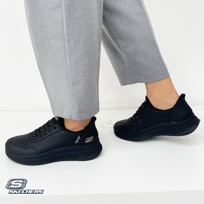 Ténis Skechers pretos com sola preta usados com calças cinzentas