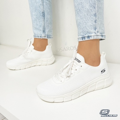 Ténis Skechers brancos em malha com sola espessa usados com calças de ganga claras