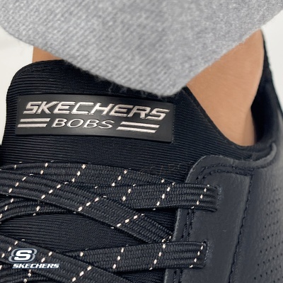 Ténis pretos Skechers Bobs com atacadores pretos com detalhes brancos e etiqueta preta e branca