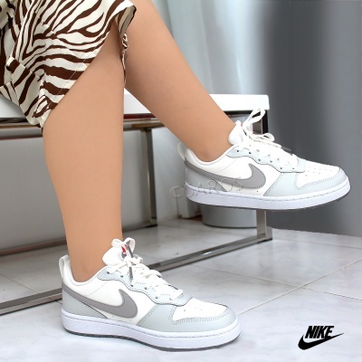 Ténis Nike brancos com detalhes cinza usados por uma pessoa sentada