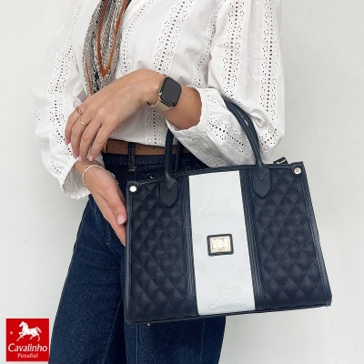 Mala de mão preta com faixa branca e logótipo Cavalinho sendo segurada