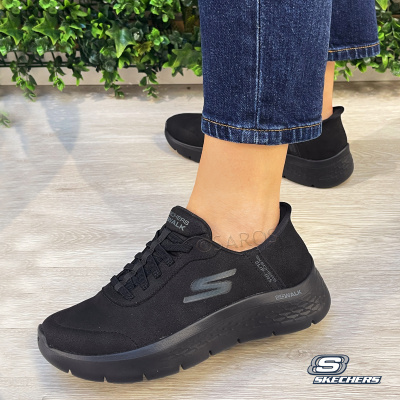 Sapatilhas Skechers Go Walk pretas com sola preta usadas com jeans e fundo com plantas