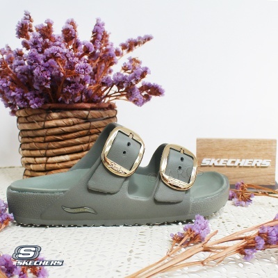 Sandália verde Skechers com fivelas douradas e flores lilás secas ao redor